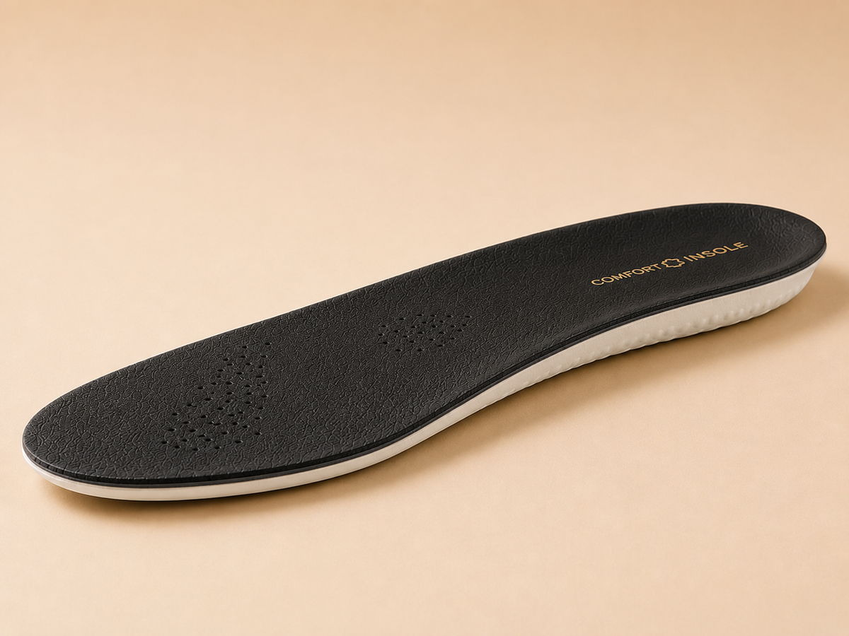 Black LeatherLine insole from a low three-quarter angle showing its slim layered edge and white dotted latex underside